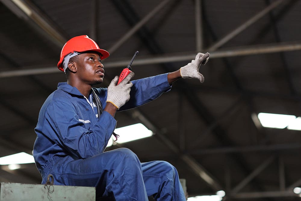 Technician engineer or worker man in protective uniform sitting and using walkie talkie radio