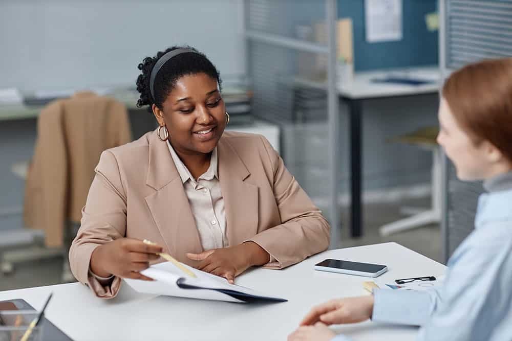 Recruiter pointing at papers on clipboard while sitting at table