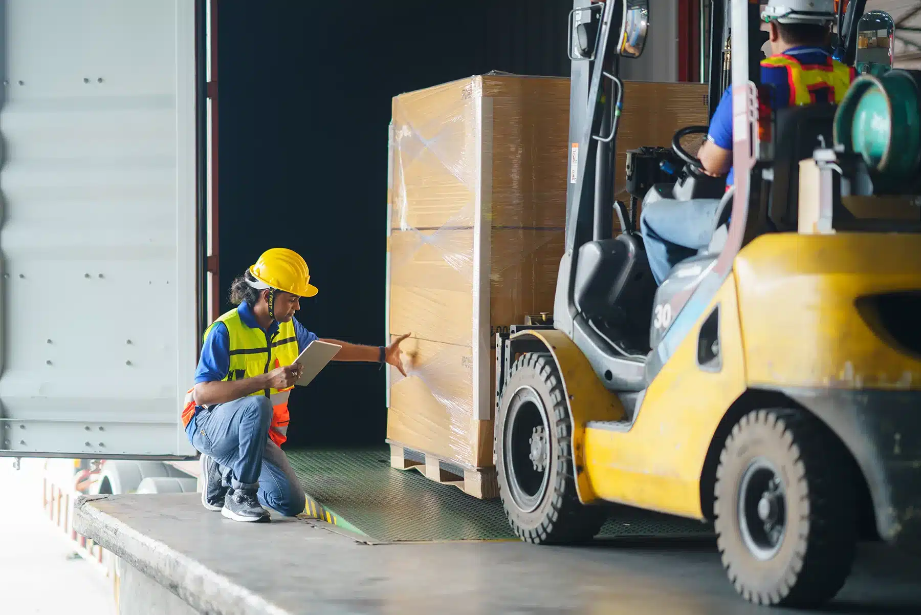 Asian forklift driver loading a shipping cargo container